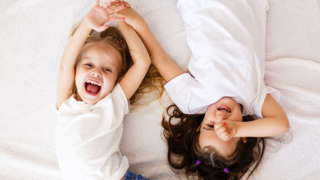 two children laughing on a white bed